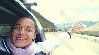 微笑着年轻的黑发女人在一辆车里玩风，开车经过美丽的山脉。 3840x2160